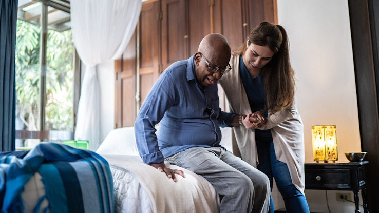 Caregiver helping someone with late stage dementia out of bed